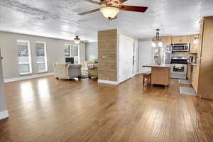 Kitchen featuring a center island, stainless steel appliances, tasteful backsplash, decorative light fixtures, and light wood-type flooring