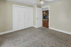 Unfurnished bedroom featuring carpet flooring, a textured ceiling, a closet, and ceiling fan