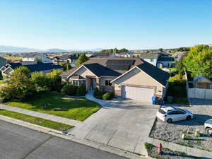 View of front of house featuring a mountain view, a front lawn, a garage, and solar panels