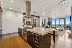 Kitchen featuring a large island, designer range, light hardwood / wood-style floors, and island range hood