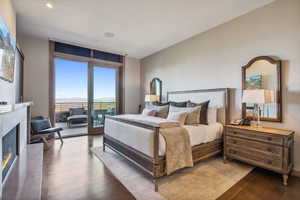 Bedroom featuring access to outside, a fireplace, and hardwood / wood-style flooring