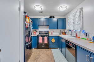 Kitchen with blue cabinetry, backsplash, sink, and black appliances