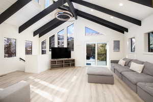 Living room with beamed ceiling, light wood-type flooring, and high vaulted ceiling