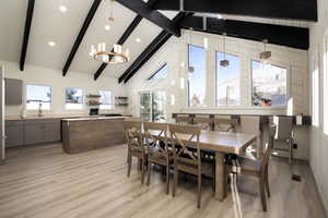 Dining room featuring a wealth of natural light, beamed ceiling, light hardwood / wood-style floors, and an inviting chandelier