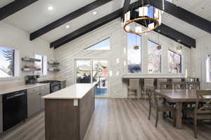 Kitchen featuring a center island, black appliances, wooden walls, light wood-type flooring, and a chandelier