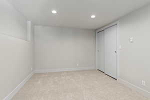 Unfurnished bedroom featuring light carpet and a closet