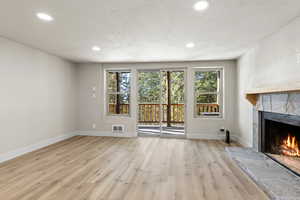 Unfurnished living room with a fireplace, plenty of natural light, and light hardwood / wood-style flooring