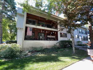 View of front of property with a balcony and a front lawn