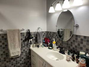 Bathroom with backsplash, vanity, and tile walls