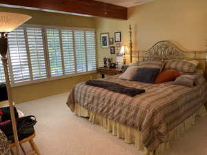 Bedroom with carpet flooring, beam ceiling, and multiple windows