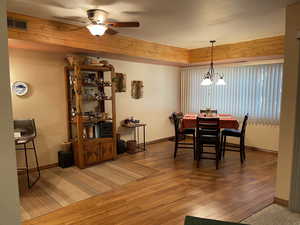 Dining space featuring a textured ceiling, ceiling fan with notable chandelier, and hardwood / wood-style flooring