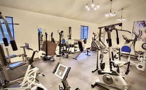 Workout area featuring a textured ceiling, an inviting chandelier, and lofted ceiling