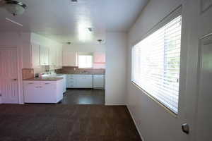 Kitchen with stove, white cabinets, dark colored carpet, white dishwasher, and sink