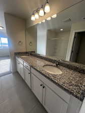 Bathroom with tile patterned floors, vanity, and a shower