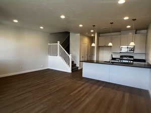 Kitchen with pendant lighting, dark hardwood / wood-style floors, gas range oven, and sink