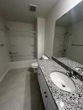 Full bathroom featuring washtub / shower combination, tile patterned flooring, vanity, and toilet