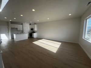 Unfurnished living room featuring sink and dark wood-type flooring