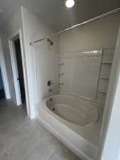 Bathroom with tile patterned flooring and shower / bath combination