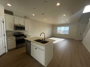 Kitchen featuring stainless steel appliances, a kitchen island with sink, dark wood-type flooring, sink, and white cabinetry