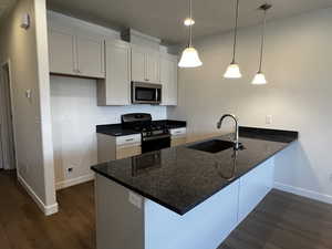 Kitchen with white cabinets, black range with gas stovetop, sink, decorative light fixtures, and kitchen peninsula