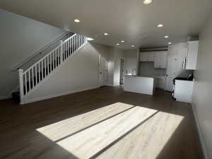 Unfurnished living room featuring dark hardwood / wood-style flooring and sink