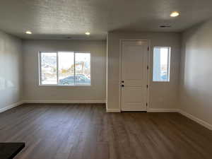 Foyer featuring a textured ceiling, dark wood-type flooring, and a healthy amount of sunlight