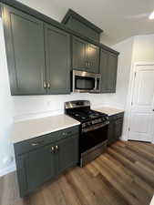 Kitchen with dark wood-type flooring and appliances with stainless steel finishes