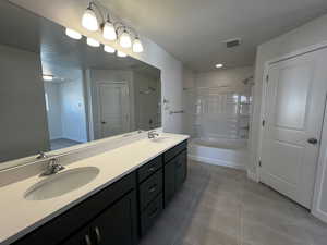 Bathroom with vanity, tile patterned floors, and tiled shower / bath combo