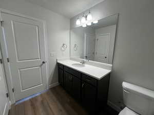 Bathroom with vanity, toilet, and wood-type flooring