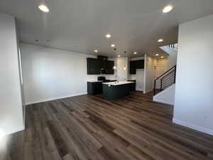 Unfurnished living room featuring dark hardwood / wood-style flooring and sink