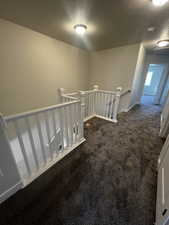 Corridor featuring dark colored carpet and a textured ceiling