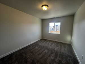 Spare room with dark carpet and a textured ceiling