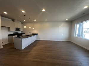 Kitchen with white cabinetry, sink, dark hardwood / wood-style floors, stove, and pendant lighting