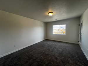 Carpeted empty room with a textured ceiling