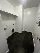 Clothes washing area with hookup for an electric dryer, hookup for a washing machine, and dark tile patterned floors