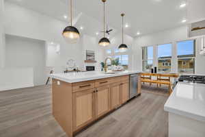 Kitchen featuring sink, a kitchen island with sink, high vaulted ceiling, stainless steel dishwasher, and light brown cabinets