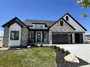 Modern inspired farmhouse featuring stone siding, a porch, an attached garage, a front yard, and board and batten siding
