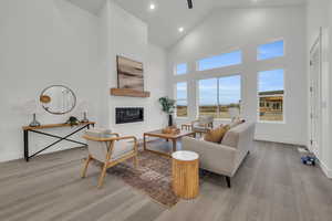 Living room featuring a fireplace, high vaulted ceiling and large windows