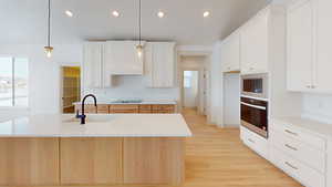 Kitchen featuring sink, an island with sink, hanging light fixtures, and black appliances