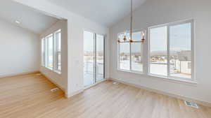 Unfurnished dining area with a wealth of natural light, light wood-type flooring, lofted ceiling, and an inviting chandelier