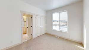 Unfurnished bedroom with multiple windows, a closet, and light colored carpet