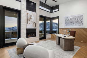 Home office featuring a mountain view, a fireplace, a towering ceiling, and light wood-type flooring