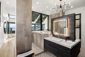 Bathroom featuring a washtub, vanity, hardwood / wood-style flooring, and an inviting chandelier