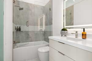 Full bathroom with tile patterned flooring, vanity, toilet, and bath / shower combo with glass door