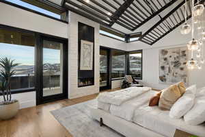 Bedroom featuring a large fireplace, a mountain view, light hardwood / wood-style floors, and multiple windows