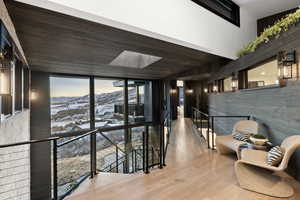 Corridor with a mountain view, a skylight, wooden walls, and light hardwood / wood-style floors