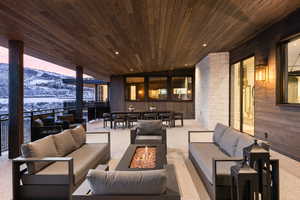 Snow covered patio with a mountain view and an outdoor living space with a fire pit