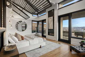 Bedroom with a mountain view, light wood-type flooring, multiple windows, and a fireplace