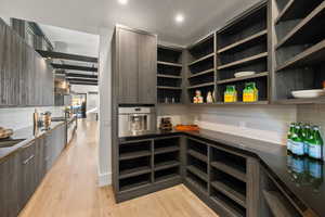 Kitchen with wall chimney exhaust hood, light hardwood / wood-style floors, decorative backsplash, and appliances with stainless steel finishes