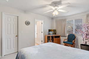 Carpeted bedroom with ceiling fan and connected bathroom